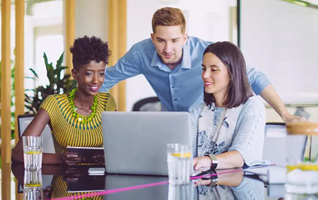 Three people in front of a laptop